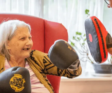 Lady in care home getting physical exercise with boxing - Applewood Healthcare