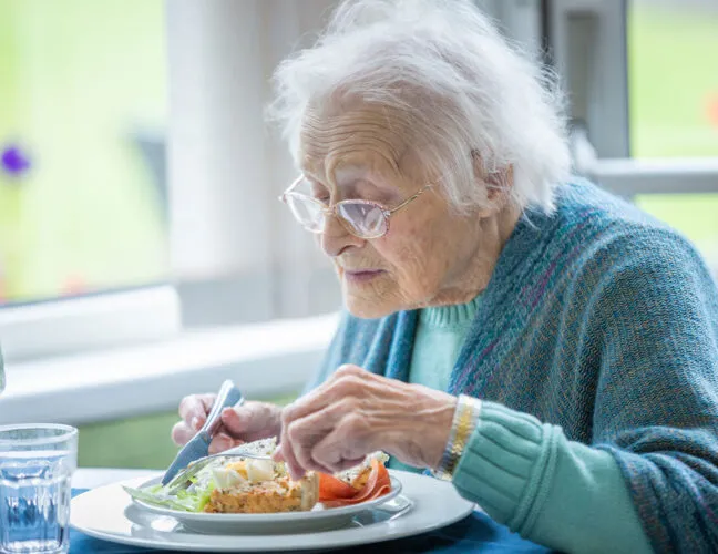 Elderly lady eating breakfast at Cherry Grove care home - Applewood Healthcare